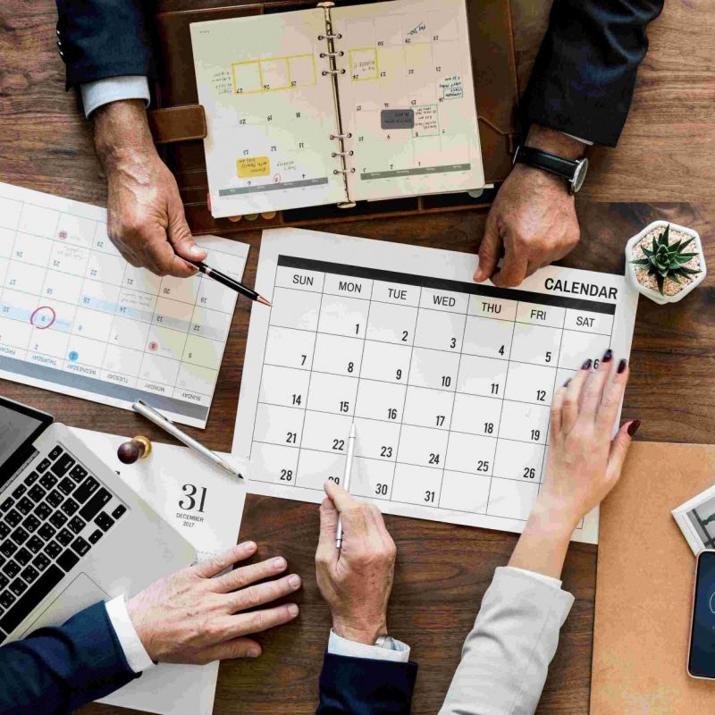 Kalender und Laptops für eine Planung liegen auf dem Tisch